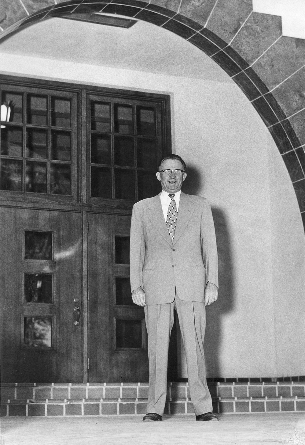 black and white portrait of a man, Roger Corbett, standing in an archway