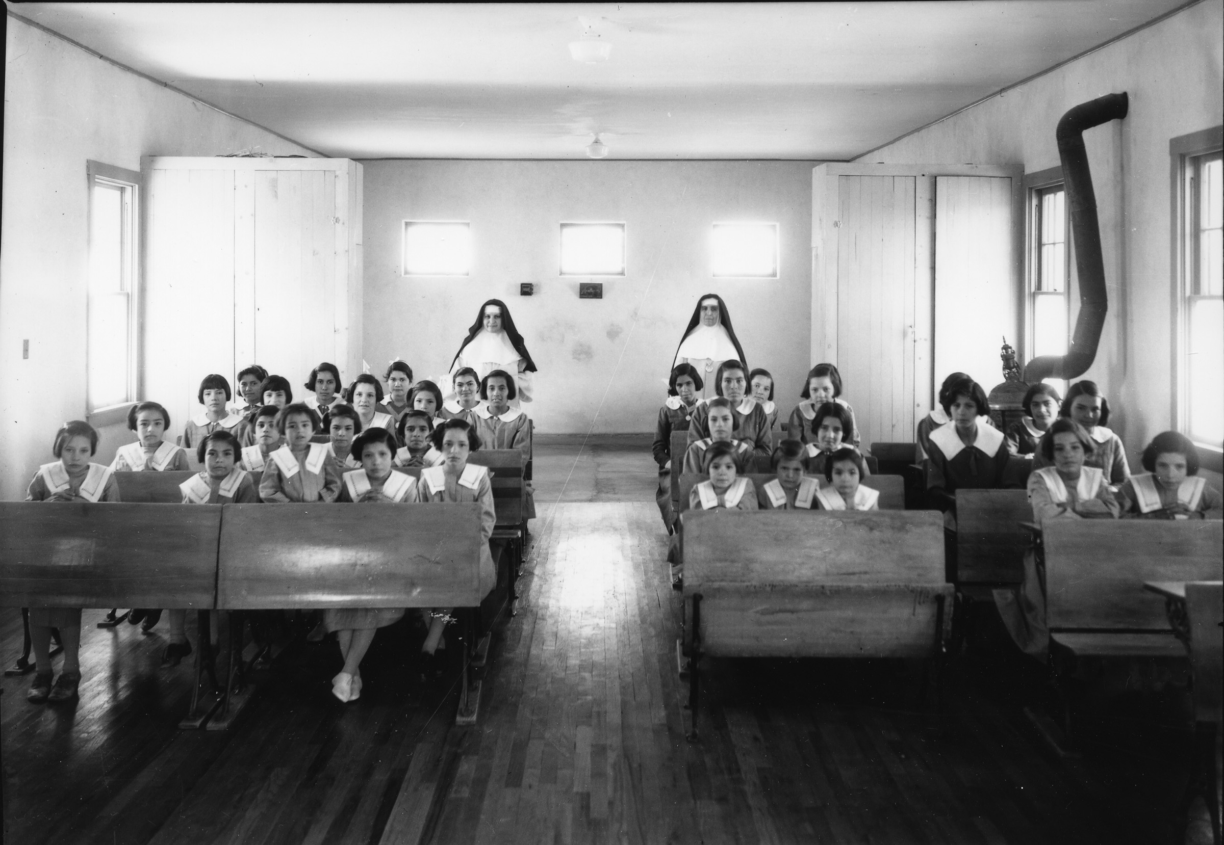 interior view of a classroom with students and nuns